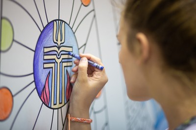 An exhibit hall visitor helps put the finishing touches on a rendering of the PC(USA) seal.