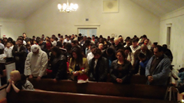 A group of people in a church bowing their heads in worship.